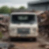 A close-up view of a scrap van in a recycling yard, showcasing its dismantled parts.